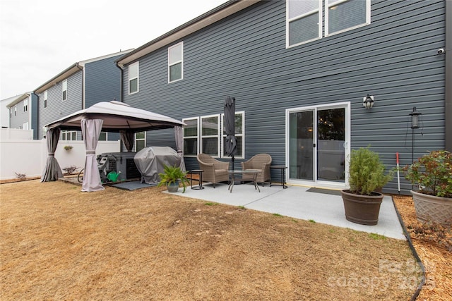 back of property featuring fence, a patio, and a gazebo