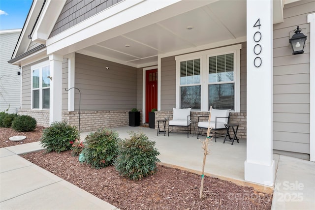 property entrance featuring covered porch and brick siding