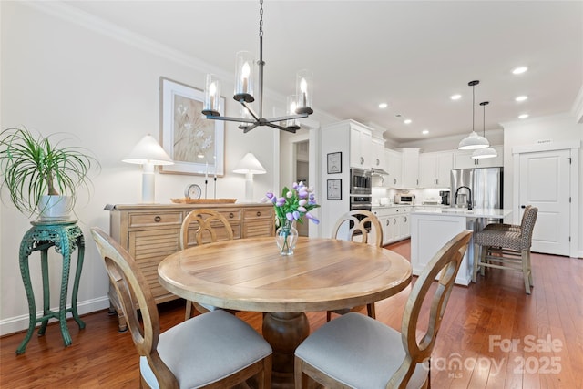 dining area featuring a chandelier, ornamental molding, wood finished floors, and recessed lighting