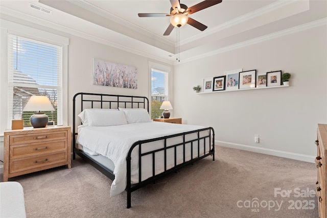 carpeted bedroom with ornamental molding, a tray ceiling, visible vents, and baseboards