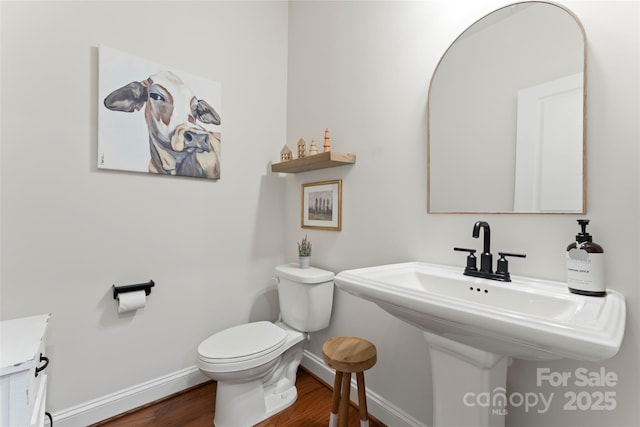 bathroom with toilet, baseboards, and wood finished floors