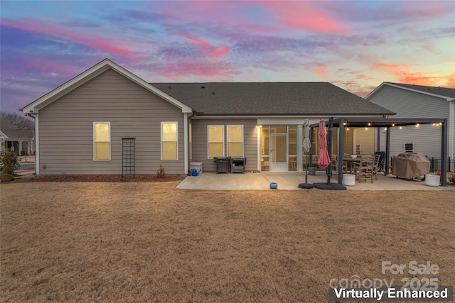 back of property with a patio, a yard, and roof with shingles