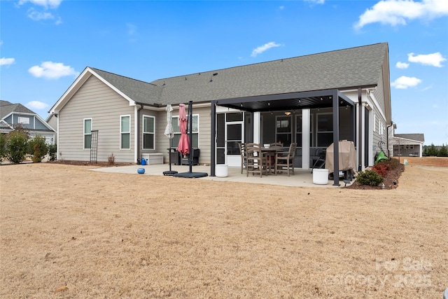 rear view of house featuring a sunroom, roof with shingles, and a patio