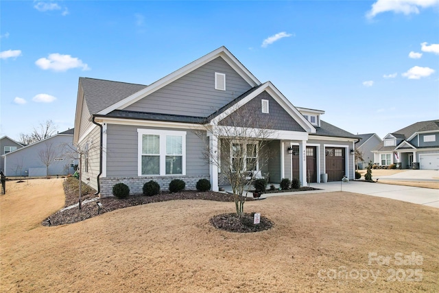 view of front of home featuring a garage, a shingled roof, a porch, and concrete driveway