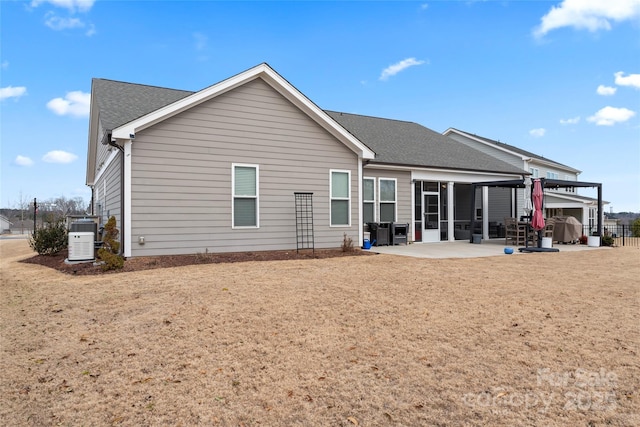 rear view of property featuring a shingled roof and a patio