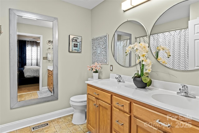 ensuite bathroom featuring double vanity, visible vents, toilet, and a sink