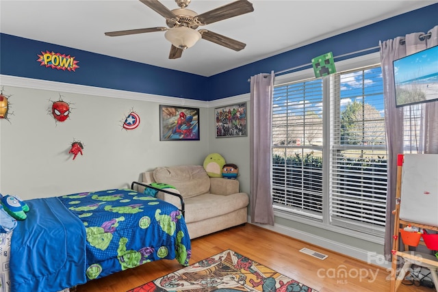 bedroom with ceiling fan, visible vents, and wood finished floors