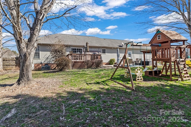 rear view of house with a playground, a yard, and a deck