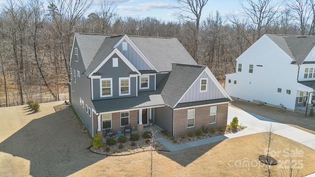 traditional-style home with driveway, brick siding, board and batten siding, and a shingled roof