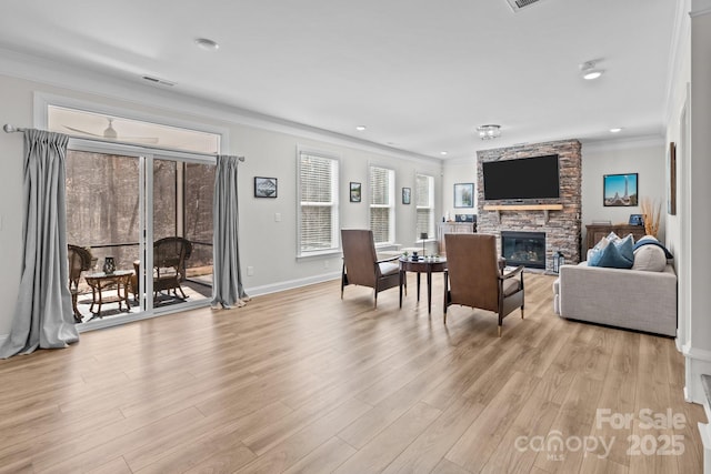 living area with a fireplace, visible vents, baseboards, ornamental molding, and light wood-type flooring