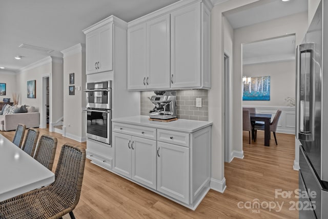 kitchen featuring white cabinets, light wood finished floors, stainless steel appliances, and light countertops