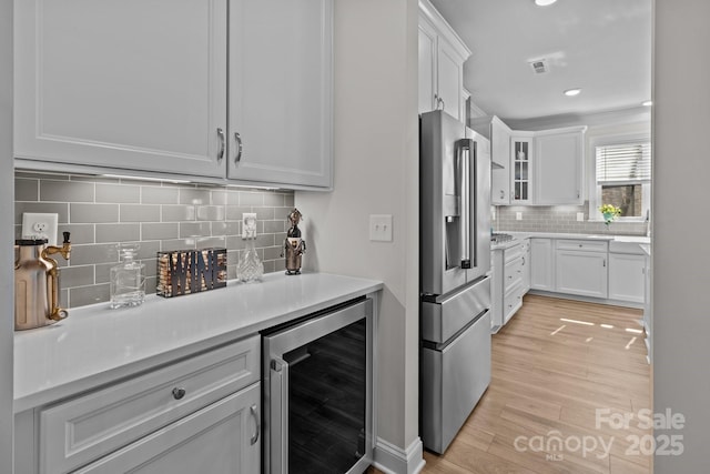 kitchen featuring glass insert cabinets, high end fridge, beverage cooler, and light countertops