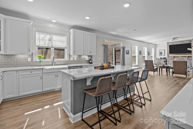 kitchen with light countertops, white cabinets, a kitchen island, a sink, and a kitchen bar