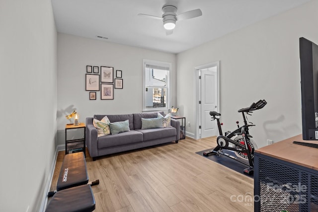 exercise area with a ceiling fan, visible vents, light wood-style flooring, and baseboards