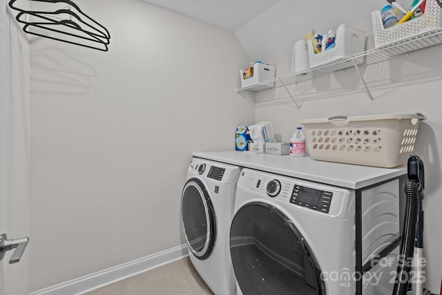 clothes washing area featuring light tile patterned floors, laundry area, washer and clothes dryer, and baseboards