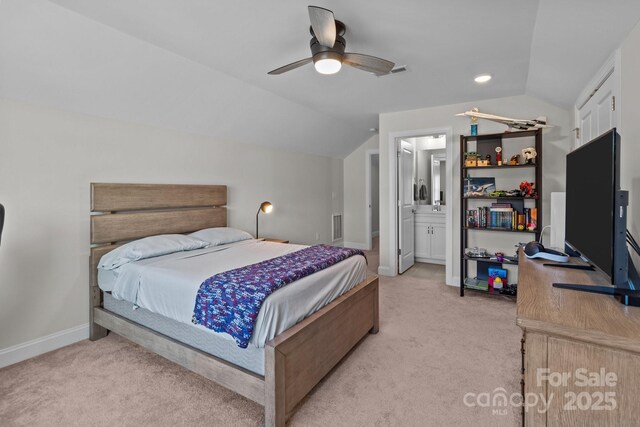 bedroom featuring lofted ceiling, light colored carpet, ensuite bathroom, ceiling fan, and baseboards