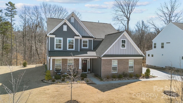 craftsman-style house featuring board and batten siding, brick siding, driveway, and roof with shingles