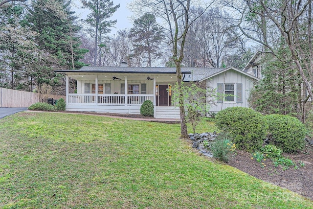 ranch-style house featuring a front yard, fence, a porch, ceiling fan, and board and batten siding