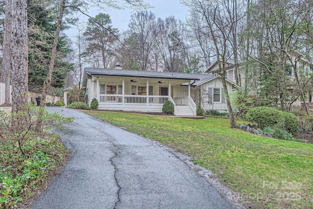 view of front of property featuring a front yard, a porch, ceiling fan, aphalt driveway, and board and batten siding