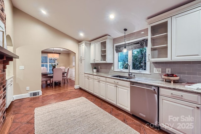 kitchen featuring visible vents, a sink, stainless steel dishwasher, tasteful backsplash, and arched walkways