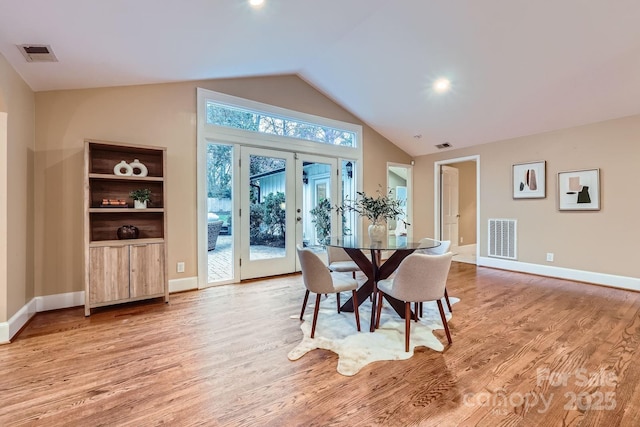 dining room with visible vents, french doors, light wood-style floors, and vaulted ceiling