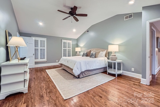 bedroom with visible vents, wood finished floors, baseboards, and vaulted ceiling