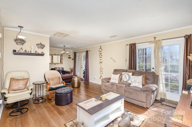 living area featuring light wood-style floors, visible vents, ornamental molding, and baseboards