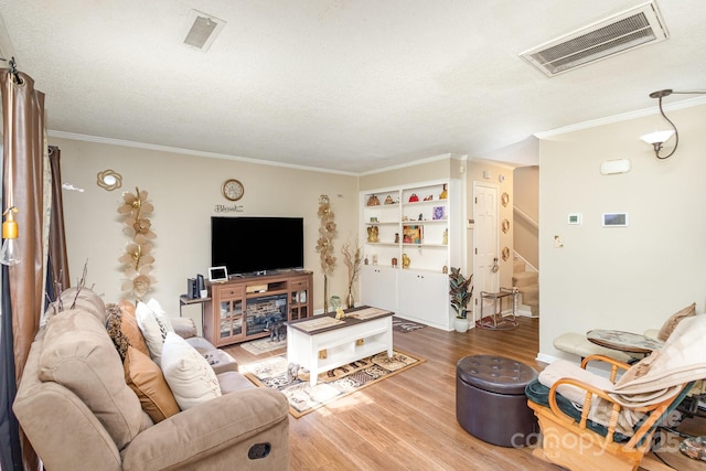 living area with visible vents, stairway, a textured ceiling, and wood finished floors