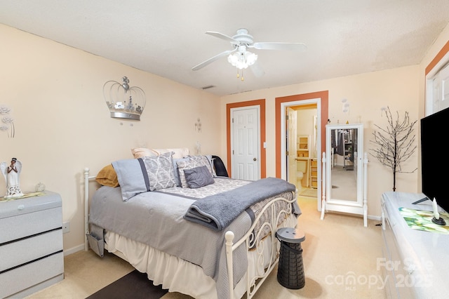 bedroom with light colored carpet, ceiling fan, baseboards, and ensuite bathroom