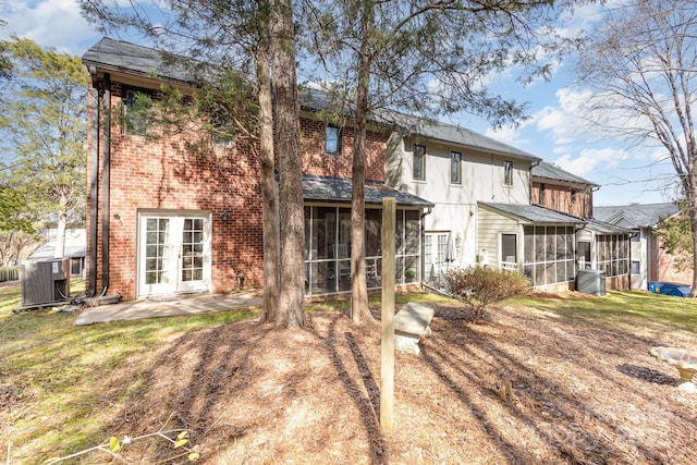 back of property featuring a sunroom, brick siding, cooling unit, and french doors