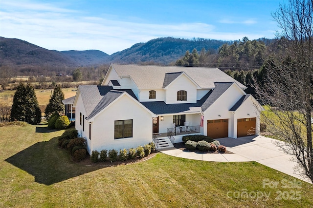 modern farmhouse featuring covered porch, an attached garage, a mountain view, driveway, and a front lawn