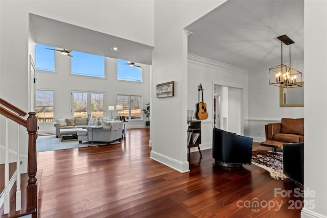 entryway with baseboards, dark wood finished floors, ornamental molding, an inviting chandelier, and stairs