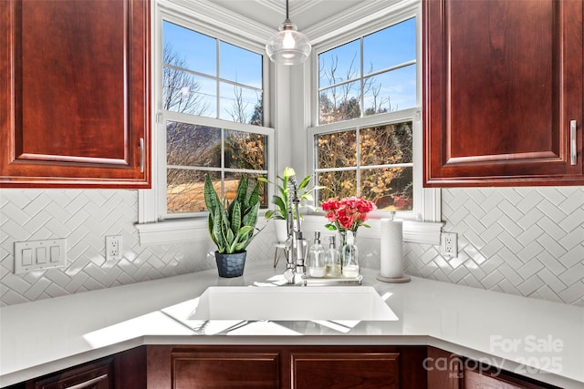 kitchen featuring a sink, light countertops, dark brown cabinets, decorative backsplash, and decorative light fixtures