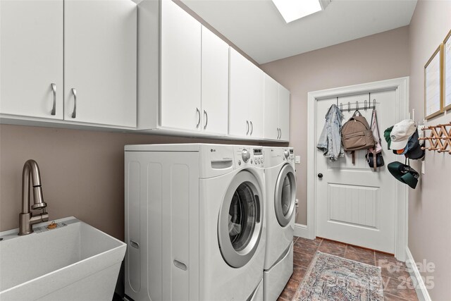 laundry area featuring cabinet space, baseboards, separate washer and dryer, and a sink