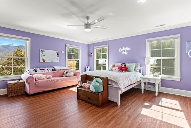 bedroom with multiple windows, visible vents, wood finished floors, and ornamental molding