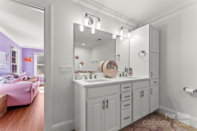 ensuite bathroom featuring a sink, ornamental molding, connected bathroom, and wood finished floors