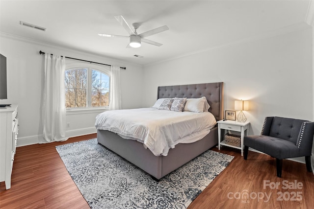 bedroom featuring dark wood finished floors, visible vents, and crown molding