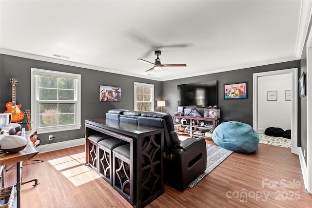 living room featuring a healthy amount of sunlight, visible vents, crown molding, and wood finished floors