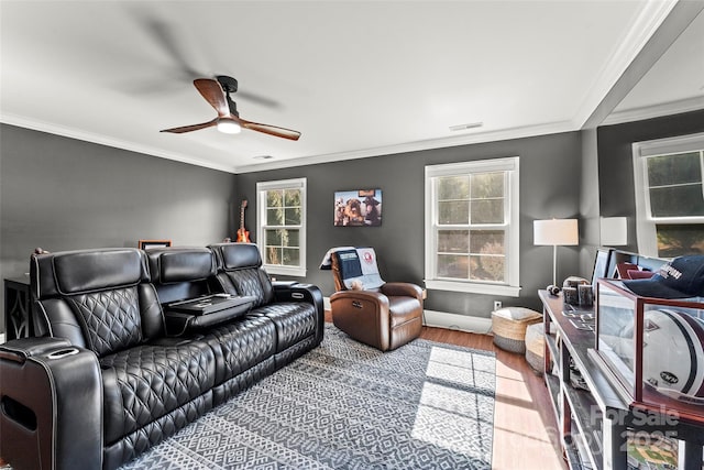 home theater room with a ceiling fan, wood finished floors, visible vents, and crown molding