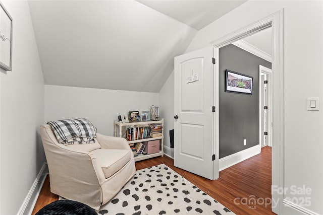 living area featuring vaulted ceiling, baseboards, and wood finished floors