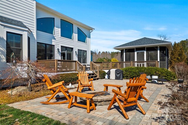 view of patio / terrace with a sunroom, an outdoor fire pit, and a deck