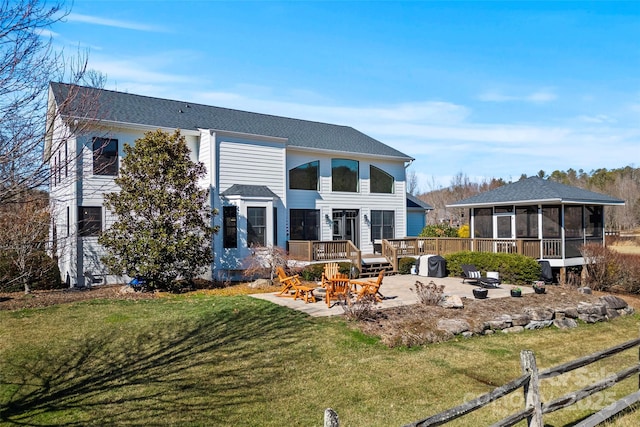 back of property with a sunroom, a yard, fence, a wooden deck, and a patio area