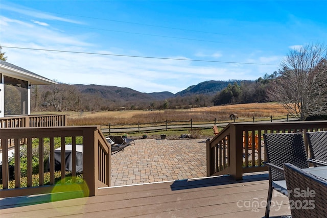 wooden deck featuring a rural view, a mountain view, fence, and a patio