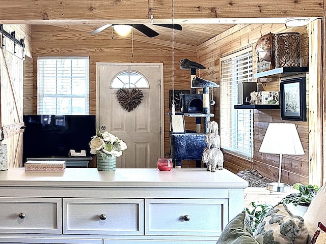 mudroom with vaulted ceiling, a barn door, and wood walls