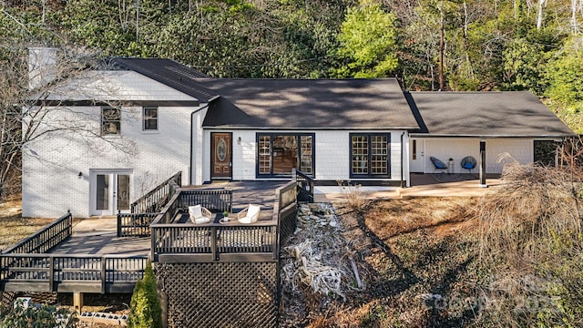 rear view of property with a deck, french doors, and brick siding