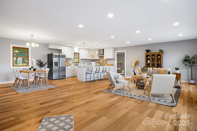 living room with recessed lighting, a notable chandelier, light wood-style flooring, and baseboards