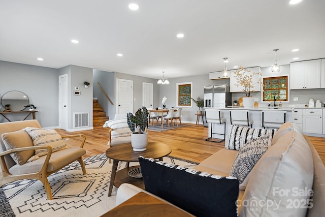 living room with light wood finished floors, visible vents, and recessed lighting