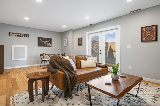 living area with visible vents, baseboards, french doors, light wood-style floors, and recessed lighting