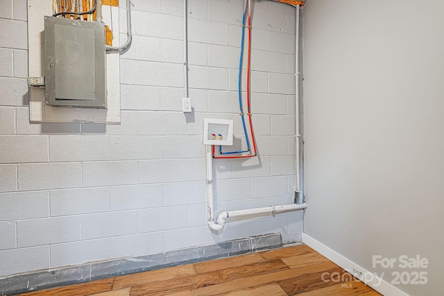 interior details featuring baseboards, wood finished floors, electric panel, and concrete block wall