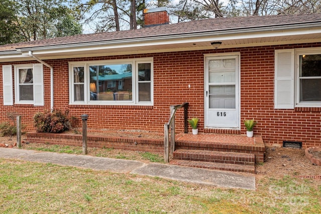 view of front of home with crawl space, a chimney, and brick siding